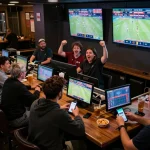 View of sports fans engaging in soi keo nha cai while watching games in a buzzing sports bar.